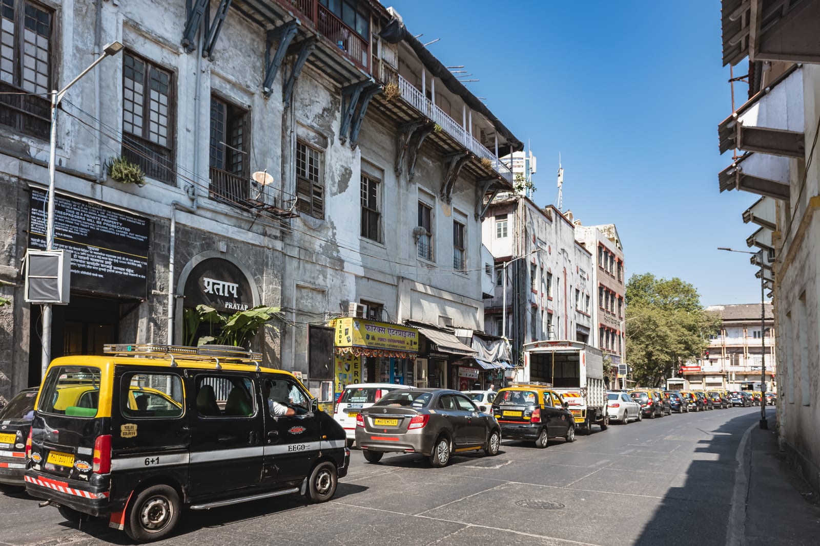 Black-and-yellow taxis on an old street in south Mumbai